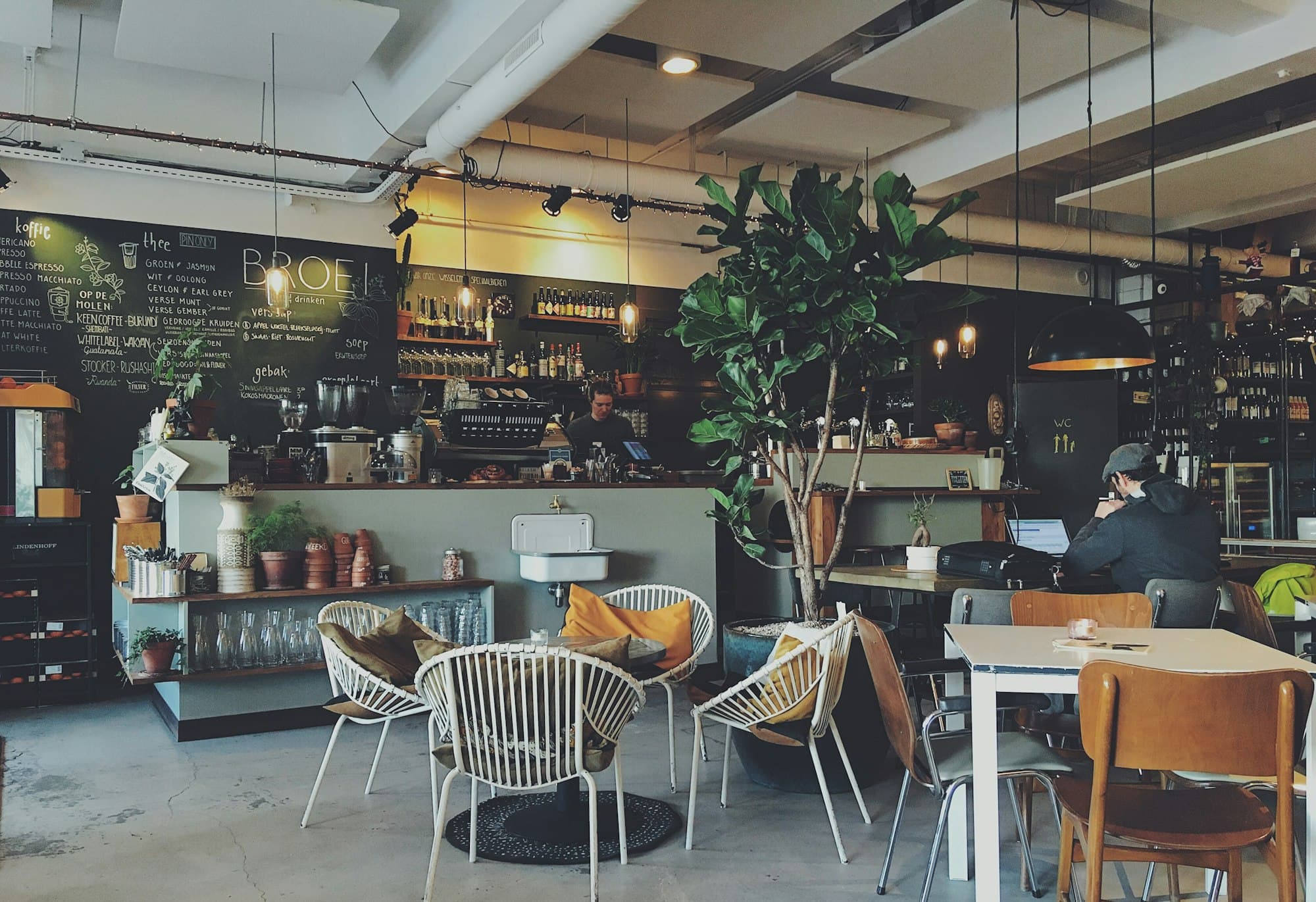 Caféraum mit Theke, Tafel und einzelnen Gästen, als Beispiel für einen lokalen Betrieb